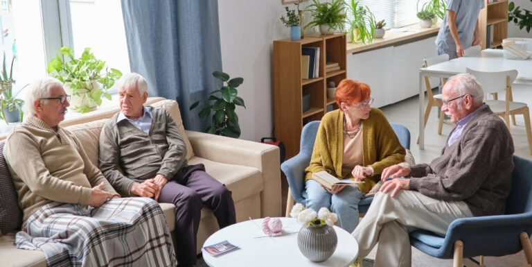 Elderly Friends Chatting Together in Cozy Lounge at Assisted Living Facility